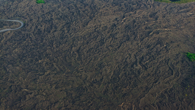 Aerial view of Mount Etna s volcanic lava field with textured rock formations and a winding road in Castiglione di Sicilia Sicily Italy. Aerial view of Mount Etna s volcanic lava field with textured rock formations and a winding road in Castiglione di Sicilia Sicily Italy.