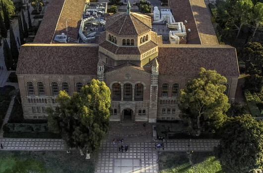 Aerial view of Royce Hall at the UCLA Campus featuring its iconic twin towers Romanesque Revival architecture red tiled roof and surrounding trees in Westwood California United States.