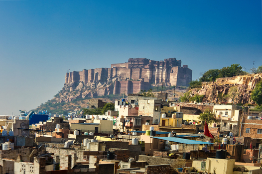 View of the historic Mehrangarh Fort rising above the dense urban rooftops of the old city under a clear blue sky in Jodhpur Rajasthan India. View of the historic Mehrangarh Fort rising above the dense urban rooftops of the old city under a clear blue sky in Jodhpur Rajasthan India.