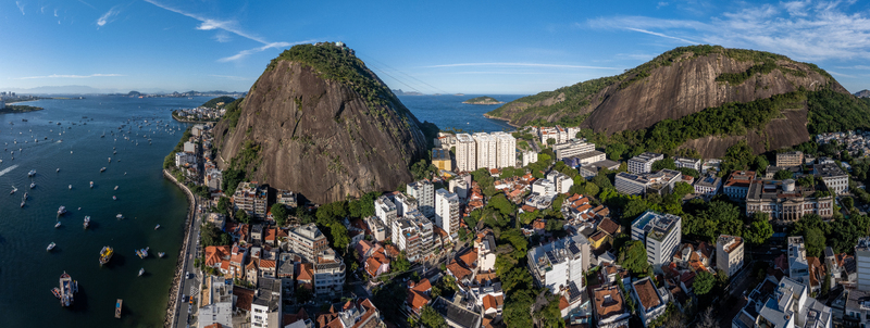 Aerial view of the Urca neighborhood and Sugarloaf Mountain featuring dense urban architecture lush vegetation and the calm waters of Guanabara Bay Rio de Janeiro Rio de Janeiro Brazil.