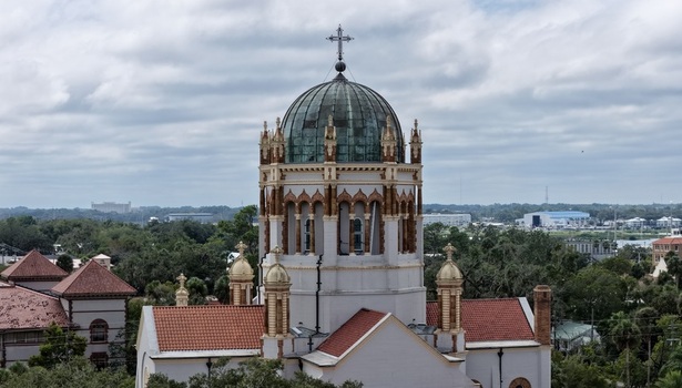 Aerial view of the ornate copper dome and terracotta roof of the historic Memorial Presbyterian Church set against a cloudy sky in St. Augustine Florida United States.