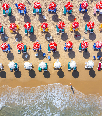 Aerial view of Bat Yam beach featuring rows of red and white umbrellas and sunbeds on golden sand with waves washing onto the shore Bat Yam Center District Israel. Aerial view of Bat Yam beach featuring rows of red and white umbrellas and sunbeds on golden sand with waves washing onto the shore Bat Yam Center District Israel.