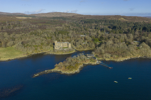 Aerial view of Dunvegan Castle and Gardens situated on a rocky promontory overlooking the sea and surrounded by lush forests Isle of Skye Scotland United Kingdom. Aerial view of Dunvegan Castle and Gardens situated on a rocky promontory overlooking the sea and surrounded by lush forests Isle of Skye Scotland United Kingdom.