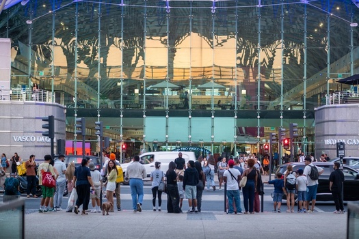 Lisboa Portugal 19 September 2026 View of the modern glass facade of Gare do Oriente with a crowd of people at a pedestrian crossing and warm evening light reflecting on the structure. Lisboa Portugal 19 September 2026 View of the modern glass facade of Gare do Oriente with a crowd of people at a pedestrian crossing and warm evening light reflecting on the structure.