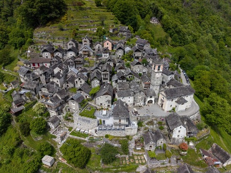 Aerial view of Corippo Albergo Diffuso featuring historic stone houses and a church tower on a lush green hillside Corippo Ticino Switzerland. Aerial view of Corippo Albergo Diffuso featuring historic stone houses and a church tower on a lush green hillside Corippo Ticino Switzerland.