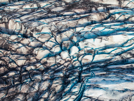 Aerial view of glacier surface with deep blue crevasses and intricate ice textures in Iceland. Aerial view of glacier surface with deep blue crevasses and intricate ice textures in Iceland.