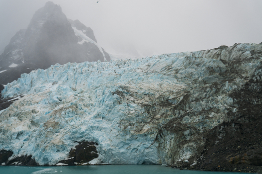 View of Drygalski Fjord glacier with its striking blue ice rugged snow capped mountains and misty atmosphere in South Georgia and the South Sandwich Islands.
