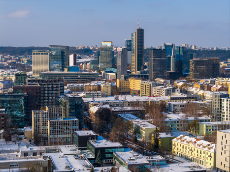 Aerial view of modern skyscrapers and snow covered rooftops under a clear blue sky in the business district of Vilnius County Lithuania.