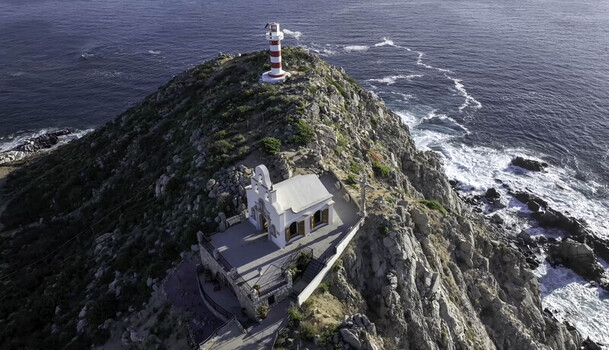 Aerial view of the lighthouse and chapel perched on the rocky cliffs overlooking the Pacific Ocean in Cabo San Lucas Baja California Sur Mexico.