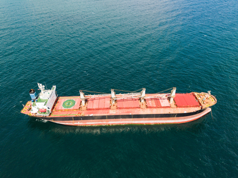 Aerial view of a large bulk carrier cargo ship with red deck and cranes navigating the deep blue waters of the Black Sea off Fichoza Beach near Varna Varna Bulgaria. Aerial view of a large bulk carrier cargo ship with red deck and cranes navigating the deep blue waters of the Black Sea off Fichoza Beach near Varna Varna Bulgaria.