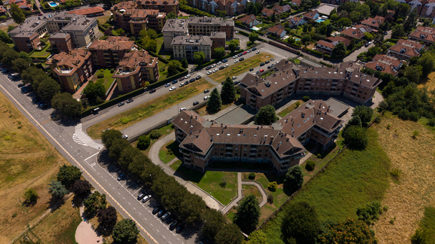 Aerial view of modern residential apartment buildings surrounded by green spaces paved roads and parked cars in a suburban neighborhood in Milan Lombardy Italy. Aerial view of modern residential apartment buildings surrounded by green spaces paved roads and parked cars in a suburban neighborhood in Milan Lombardy Italy.