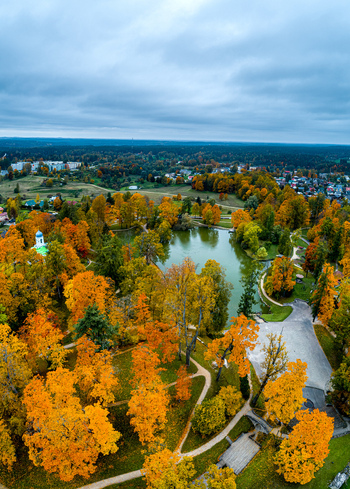 Aerial view of vibrant autumn foliage in Cesis Castle Park featuring a serene pond winding pathways and a historic church building in Cesis Cesis Municipality Latvia. Aerial view of vibrant autumn foliage in Cesis Castle Park featuring a serene pond winding pathways and a historic church building in Cesis Cesis Municipality Latvia.