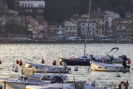 Lerici Italy 08 March 2026 View of small boats bobbing gently in the harbor reflecting the golden light of the setting sun against the backdrop of the pastel colored buildings..