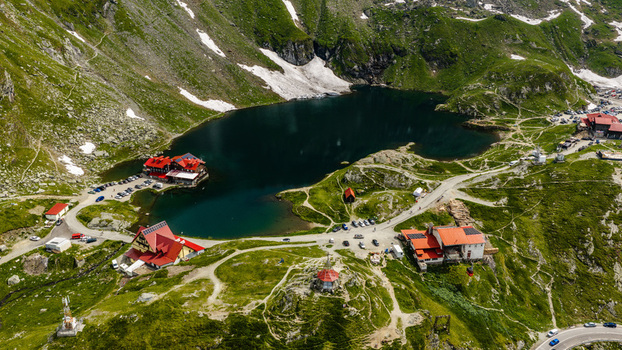 Aerial view of Balea Lake and surrounding mountain chalets along the Transfagarasan road with patches of snow on the slopes in Curtea de Arges Judetul Arges Romania.