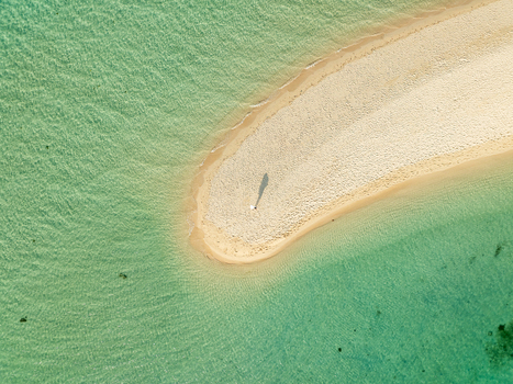 Aerial view of Malcapuya Island sandbar surrounded by clear turquoise water with a person standing on the white sand in Coron Mimaropa Philippines. Aerial view of Malcapuya Island sandbar surrounded by clear turquoise water with a person standing on the white sand in Coron Mimaropa Philippines.