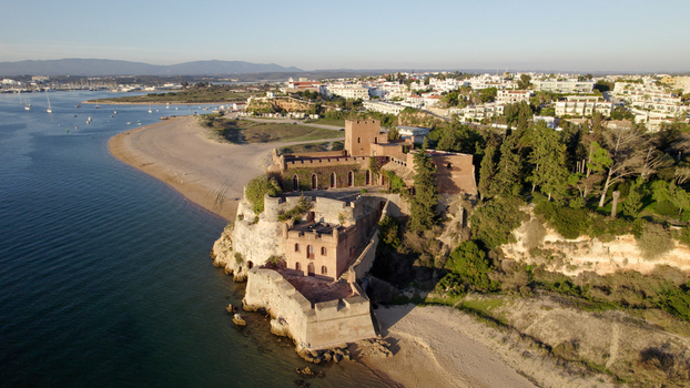 Aerial view of the historic Castelo de Sao Joao do Arade situated on a rocky cliff overlooking the beach and the Arade River estuary in Ferragudo Faro District Portugal.