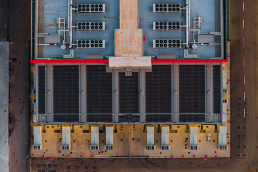 Aerial view of a modern datacenter roof featuring rows of industrial HVAC cooling units and solar panels in Settecamini Lazio Italy.