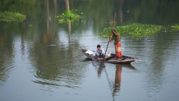 View of fishermen in a wooden boat on a river in Bangladesh.