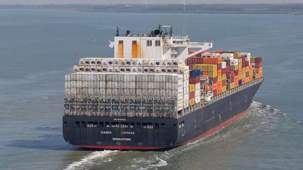 Terneuzen Netherlands 08 April 2026 Aerial view of the Xiamen Express container ship loaded with colorful cargo sailing on the water with wind turbines in the distance. Terneuzen Netherlands 08 April 2026 Aerial view of the Xiamen Express container ship loaded with colorful cargo sailing on the water with wind turbines in the distance.