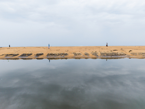 Aerial view of a sandy shoreline with people walking along the beach and a calm water surface reflecting the overcast sky in Galle Southern Province Sri Lanka. Aerial view of a sandy shoreline with people walking along the beach and a calm water surface reflecting the overcast sky in Galle Southern Province Sri Lanka.