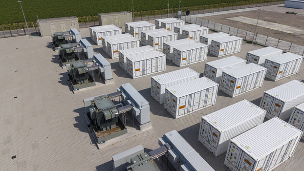 Aerial view of the Battery Energy Storage System at Wind Park with rows of white shipping containers and electrical transformers on a paved site in Dronten Flevoland Netherlands. Aerial view of the Battery Energy Storage System at Wind Park with rows of white shipping containers and electrical transformers on a paved site in Dronten Flevoland Netherlands.