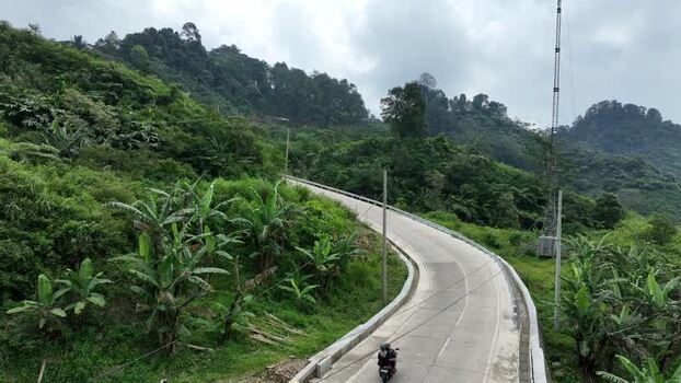 Aerial view of a winding road through lush green hills Indonesia.