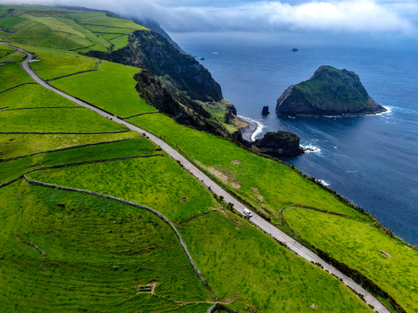 Aerial view of the vivid green fields meet the rugged cliffs and deep blue sea near Estrada do Farol Flores A&ccedil;ores Portugal.