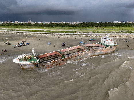Chattogram Bangladesh 22 September 2026 Aerial view of a large rusted cargo ship beached on the sandy shore with people walking nearby under dark storm clouds.