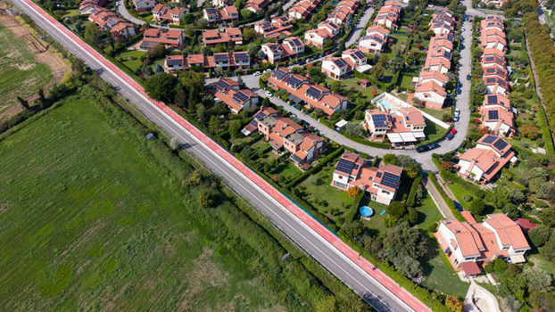 Aerial view of private houses with solar panels and green gardens next to a road and agricultural fields in Mediglia Lombardy Italy. Aerial view of private houses with solar panels and green gardens next to a road and agricultural fields in Mediglia Lombardy Italy.