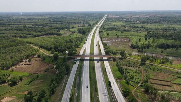 Aerial view of the highway and overpass bridge surrounded by lush green fields and trees in Cipeundeuy West Java Indonesia. Aerial view of the highway and overpass bridge surrounded by lush green fields and trees in Cipeundeuy West Java Indonesia.