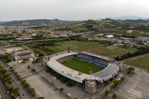 Aerial view of Stadio Riviera delle Palme a football stadium with a green pitch and blue seating surrounded by open fields roads San Benedetto del Tronto Marche Italy.