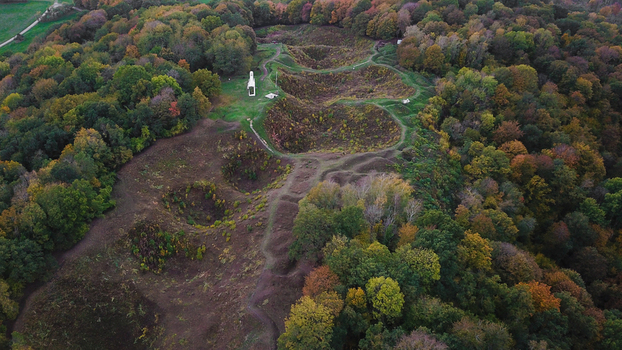 Aerial view of the World War 1 battlefield site of Vauquois Hill featuring deep craters and autumn foliage in the surrounding forest in Vauquois Grand Est France.