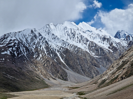View of the rugged Penzi La road winding through the snow capped Himalayan peaks and rocky valley floor in Zanskar Ladakh India.