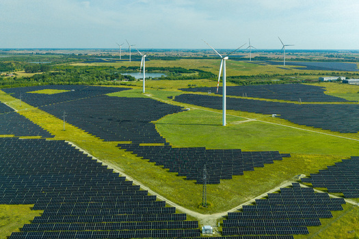 Aerial view of a large solar farm with wind turbines in a rural landscape in Poland.