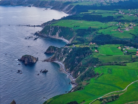 Aerial view of the rugged coastline of Silence Beach Viewpoint with steep cliffs and lush green fields in Cudillero Asturias Spain.