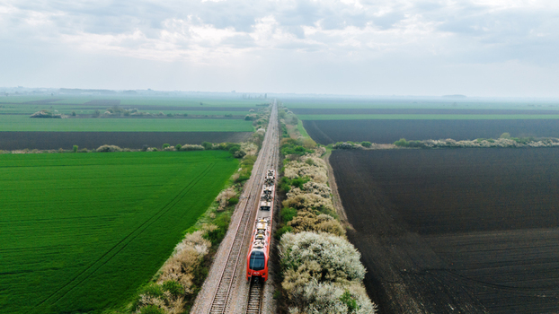 Aerial view of a vibrant red train slicing through the heart of the country flanked by contrasting green and brown fields Sremska Mitrovica Vojvodina Serbia. Aerial view of a vibrant red train slicing through the heart of the country flanked by contrasting green and brown fields Sremska Mitrovica Vojvodina Serbia.
