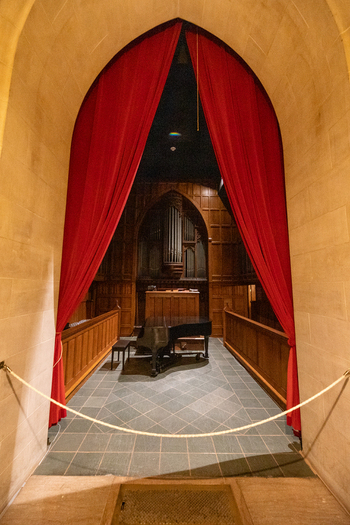 Washington United States 06 May 2025 View of the Washington National Cathedral interior featuring a grand piano and pipe organ framed by a stone archway and red curtains.