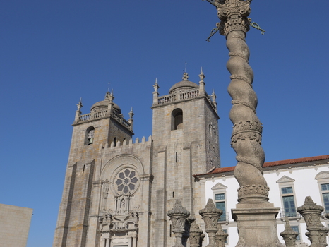 View of the historic Porto Cathedral with its twin towers and rose window featuring a decorative stone column in the foreground under a clear blue sky in Porto Porto District Portugal. View of the historic Porto Cathedral with its twin towers and rose window featuring a decorative stone column in the foreground under a clear blue sky in Porto Porto District Portugal.