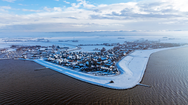 Aerial view of the snow covered coastal town of Hindeloopen with its historic harbor dikes and frozen fields in Hindeloopen Friesland Netherlands. Aerial view of the snow covered coastal town of Hindeloopen with its historic harbor dikes and frozen fields in Hindeloopen Friesland Netherlands.