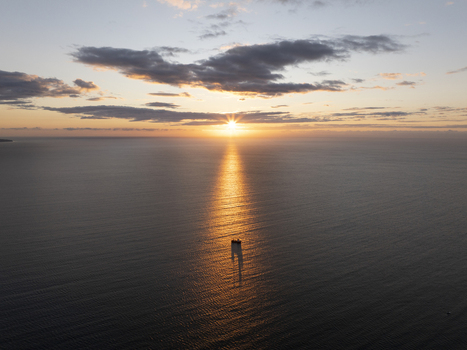 Aerial view of a small boat sailing on the calm sea during a golden sunset with a vibrant sky and sun reflection on the water near Nessebar Burgas Bulgaria. Aerial view of a small boat sailing on the calm sea during a golden sunset with a vibrant sky and sun reflection on the water near Nessebar Burgas Bulgaria.