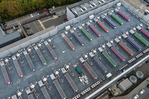 Aerial view of a data center roof featuring rows of industrial cooling units with colorful accents and ventilation systems in the United Kingdom.
