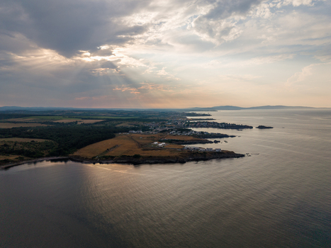 Aerial view of Arapya coastline featuring rocky shores golden fields and calm sea under a dramatic cloudy sky with sunbeams in Burgas Bulgaria. Aerial view of Arapya coastline featuring rocky shores golden fields and calm sea under a dramatic cloudy sky with sunbeams in Burgas Bulgaria.