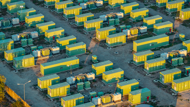 Aerial view of modular battery storage containers and electrical equipment at a modern energy facility illuminated by warm evening sunlight Italy. Aerial view of modular battery storage containers and electrical equipment at a modern energy facility illuminated by warm evening sunlight Italy.