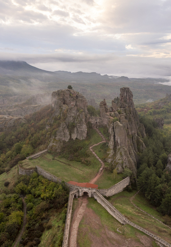 Aerial view of Belogradchik Fortress surrounded by dramatic rock formations lush green forests and historic stone walls under a soft cloudy sky in Belogradchik Vidin Bulgaria. Aerial view of Belogradchik Fortress surrounded by dramatic rock formations lush green forests and historic stone walls under a soft cloudy sky in Belogradchik Vidin Bulgaria.