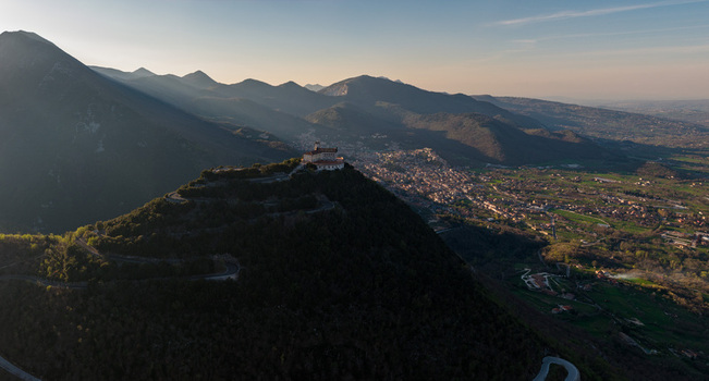 Aerial view of Santuario del Santissimo Salvatore on a mountain peak with a winding road and the town in the valley in Montella Campania Italy. Aerial view of Santuario del Santissimo Salvatore on a mountain peak with a winding road and the town in the valley in Montella Campania Italy.