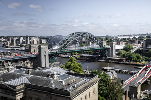 Aerial view of the iconic Tyne Bridge spanning the River Tyne with the Sage Gateshead and historic urban architecture in Newcastle upon Tyne England United Kingdom. Aerial view of the iconic Tyne Bridge spanning the River Tyne with the Sage Gateshead and historic urban architecture in Newcastle upon Tyne England United Kingdom.