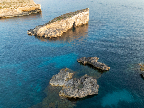 Aerial view of turquoise waters meeting rugged rock formations creating a stunning contrast of blues and browns Blue lagoon Comino Malta. Aerial view of turquoise waters meeting rugged rock formations creating a stunning contrast of blues and browns Blue lagoon Comino Malta.