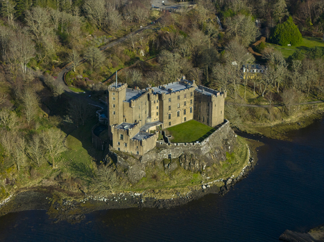 Aerial view of Dunvegan Castle and Gardens a historic stone fortress on a rocky cliff overlooking the sea surrounded by lush woodland and gardens Isle of Skye Scotland United Kingdom. Aerial view of Dunvegan Castle and Gardens a historic stone fortress on a rocky cliff overlooking the sea surrounded by lush woodland and gardens Isle of Skye Scotland United Kingdom.