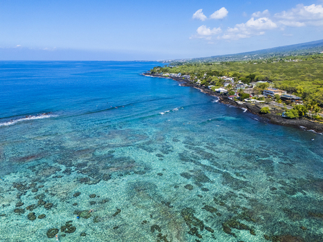 Aerial view of Kahalu u Beach Park featuring turquoise waters and coral reefs along the volcanic coastline with lush greenery in Kailua Kona Hawaii United States. Aerial view of Kahalu u Beach Park featuring turquoise waters and coral reefs along the volcanic coastline with lush greenery in Kailua Kona Hawaii United States.