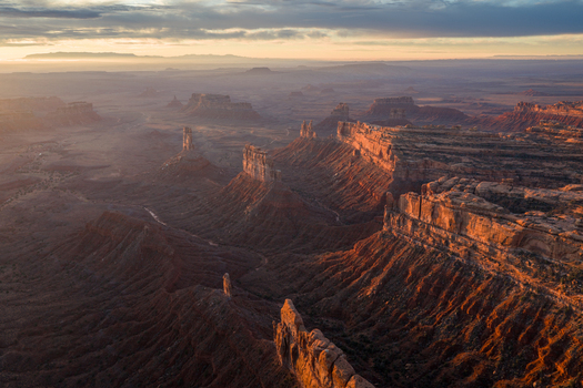 Aerial view of the dramatic rock formations and mesas of Bears Ears at golden hour with deep canyons and rugged desert terrain in San Juan County Utah United States. Aerial view of the dramatic rock formations and mesas of Bears Ears at golden hour with deep canyons and rugged desert terrain in San Juan County Utah United States.